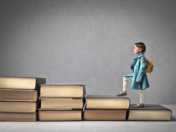 Mädchen steigt eine Büchertreppe hoch.